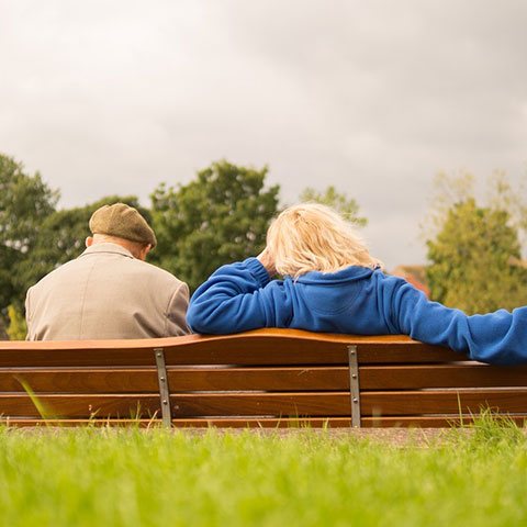 Elderly man and lady sat on a bench