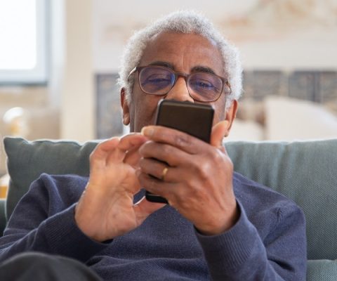 elderly man using phone to address loneliness and fight mental health problems